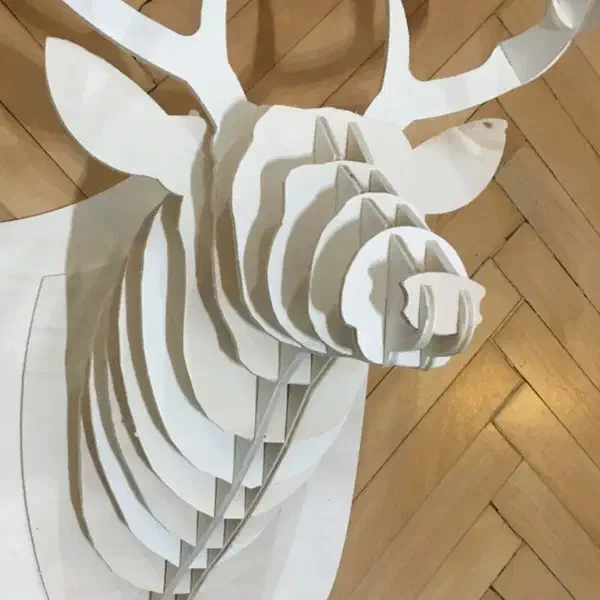 A layered plywood deer head with antlers mounted on a wall.