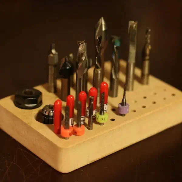A rounded wooden block drilled with holes to store CNC router bits.