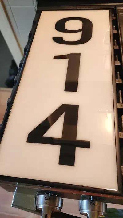 Finished white Corian address panel with tall black 914 numbers inside a dark frame
