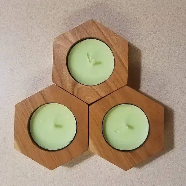 Three hexagonal wooden tealight holders arranged together around pale green candles