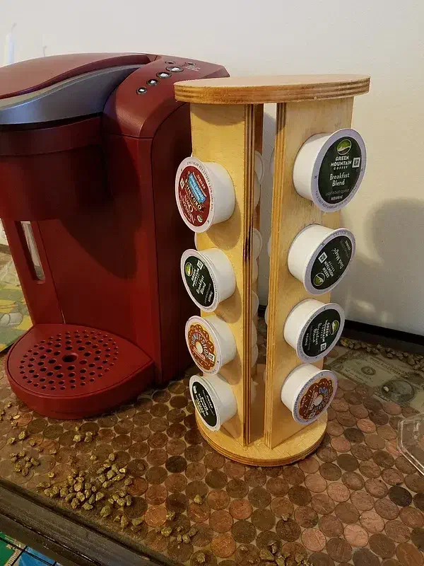 A plywood tower holding coffee pods beside a red coffee machine