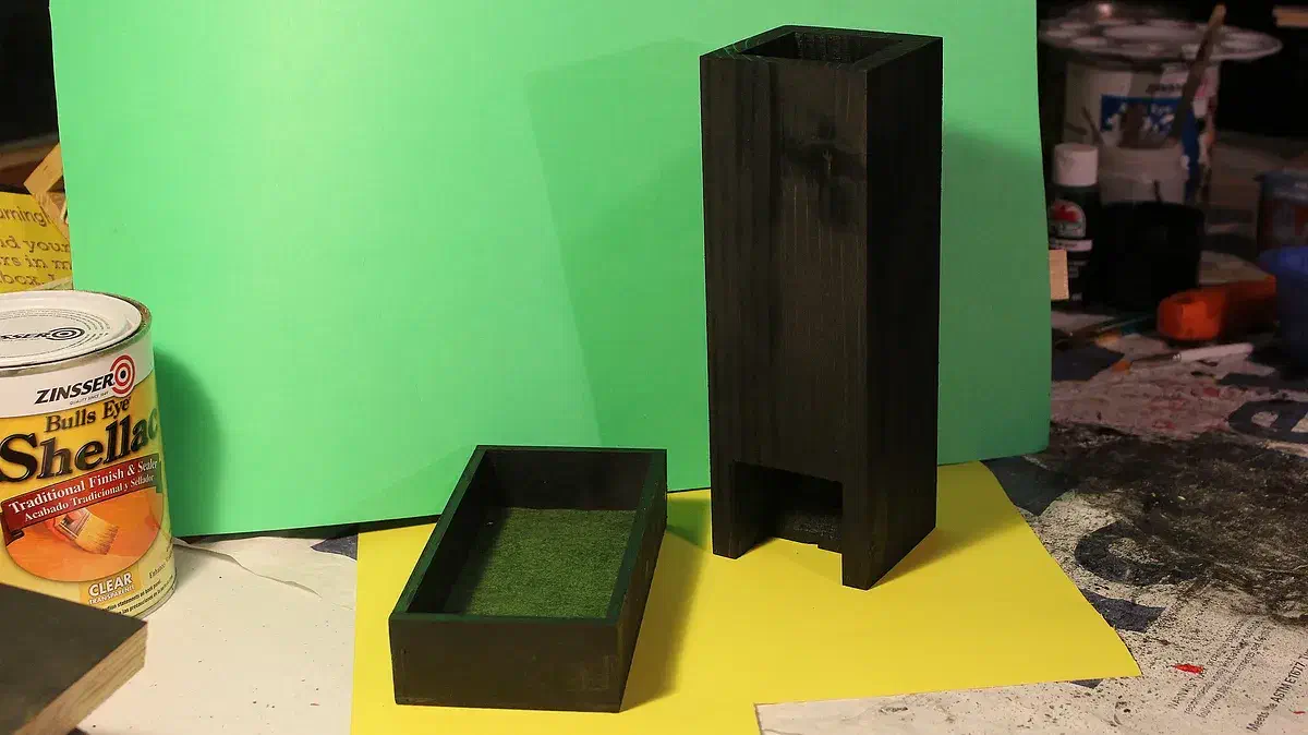 Black-finished wooden dice tower beside a shallow tray lined with green felt