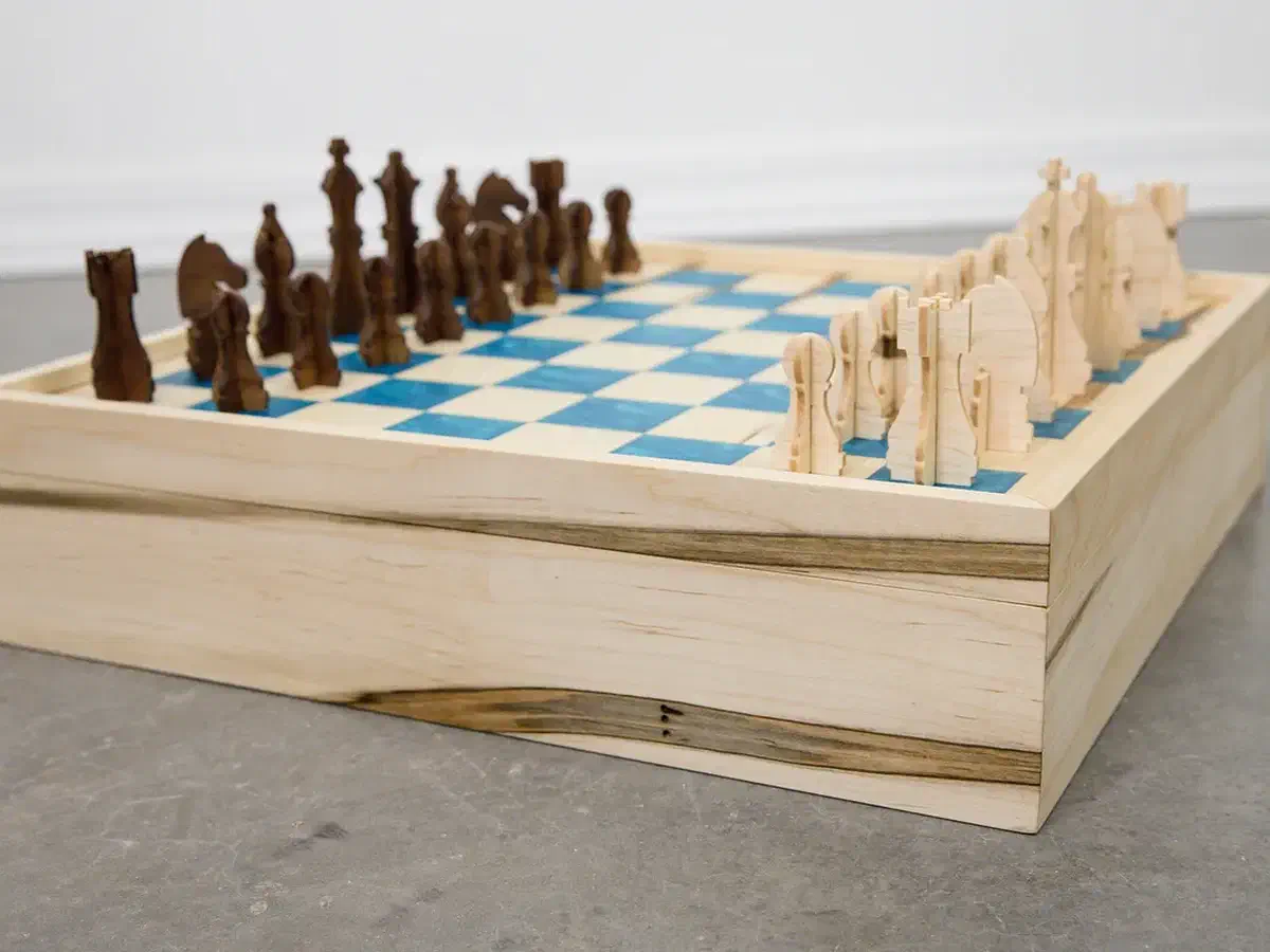 Finished chess and checkers game box with natural and dark wooden pieces arranged on a blue-inlay board