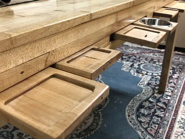 Carved wooden trays fitted along a gaming table, including a separate metal cup holder
