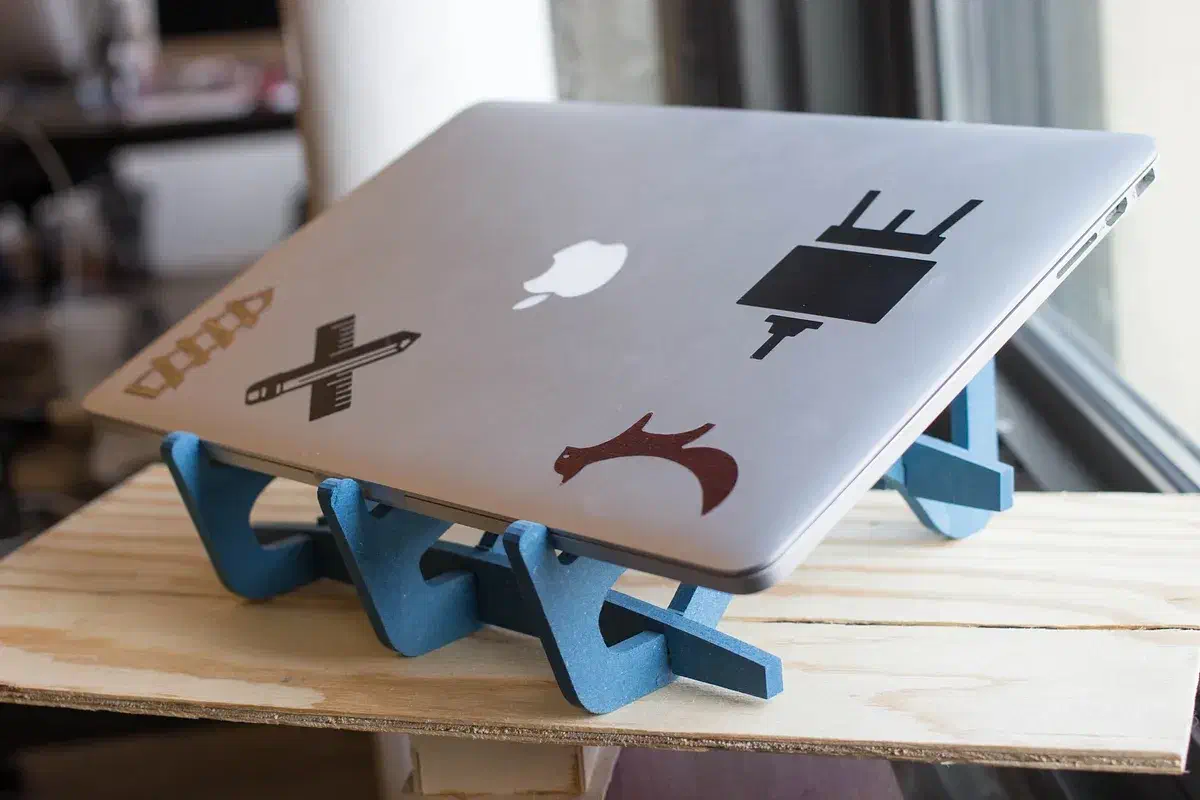 A silver laptop on a blue interlocking stand with shaped openings in its side panels