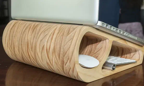 A rounded laminated plywood laptop stand with a white keyboard stored in its opening