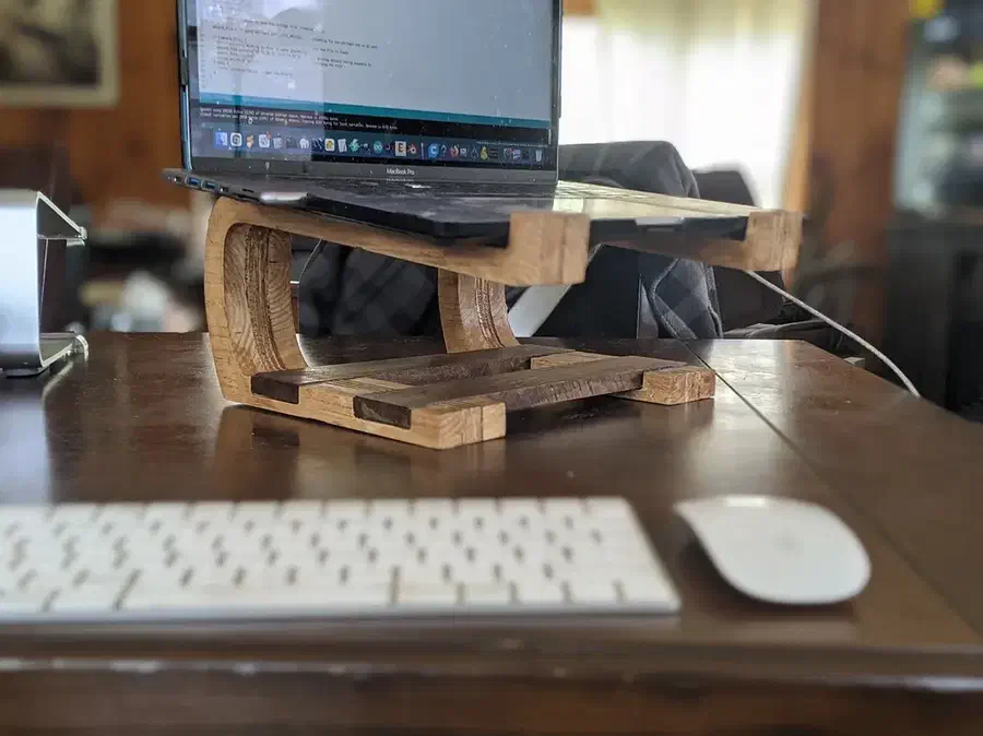 A laptop resting on a curved laminated plywood stand beside a separate keyboard