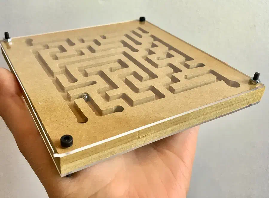 A finished covered MDF ball maze held in a hand