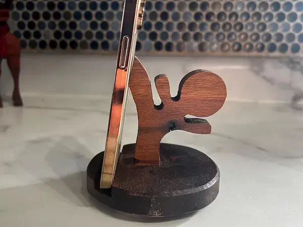 Wooden ninja silhouette supporting a phone on a round dark base