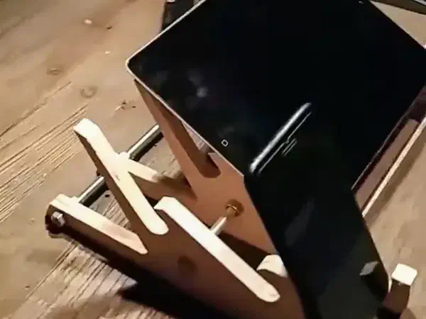 Plywood multi-slot stand holding a phone and tablet on a workshop table