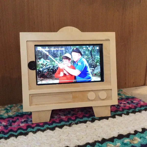 Finished plywood television-shaped stand holding a phone horizontally