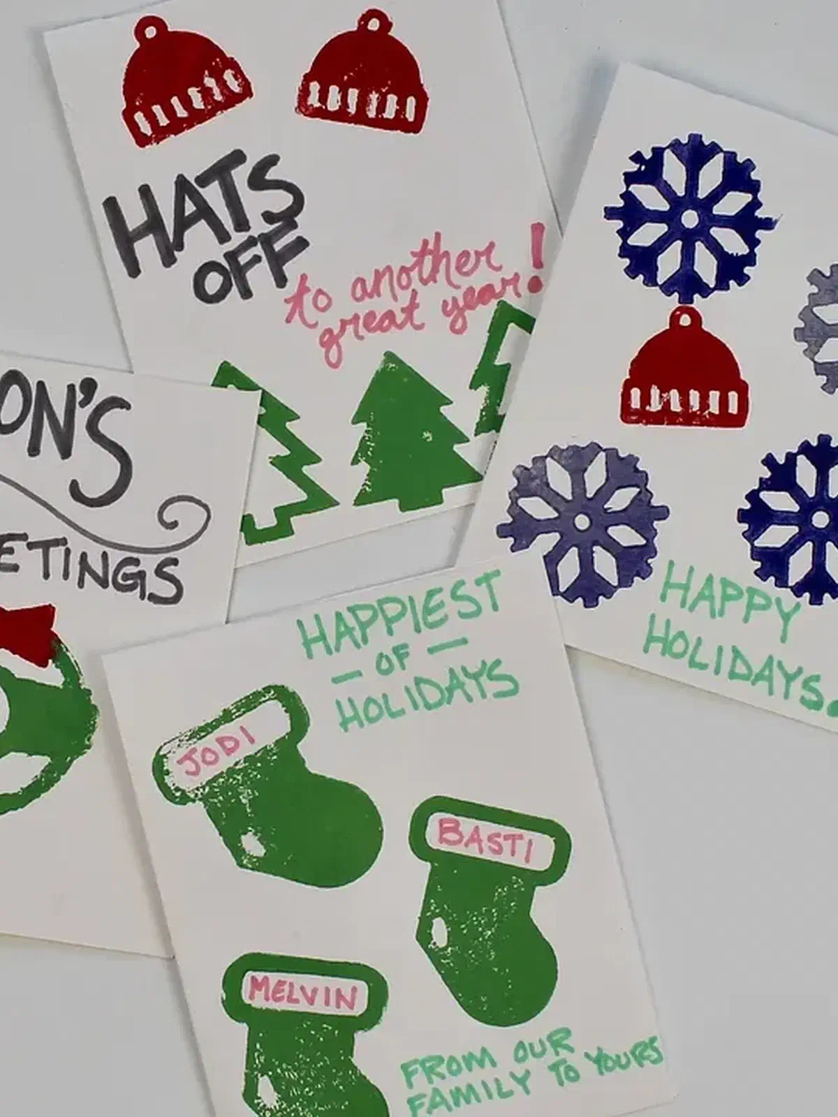 Hand-stamped holiday cards with colorful hats, mittens, snowflakes and greeting text