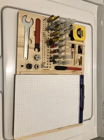 Maple wall board with router bits, wrench, yellow tape measure and clipped graph-paper pad