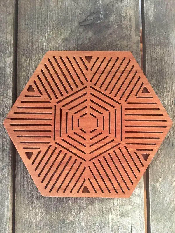 Cherry wood hexagonal trivet with radial snowflake-like slots on weathered boards