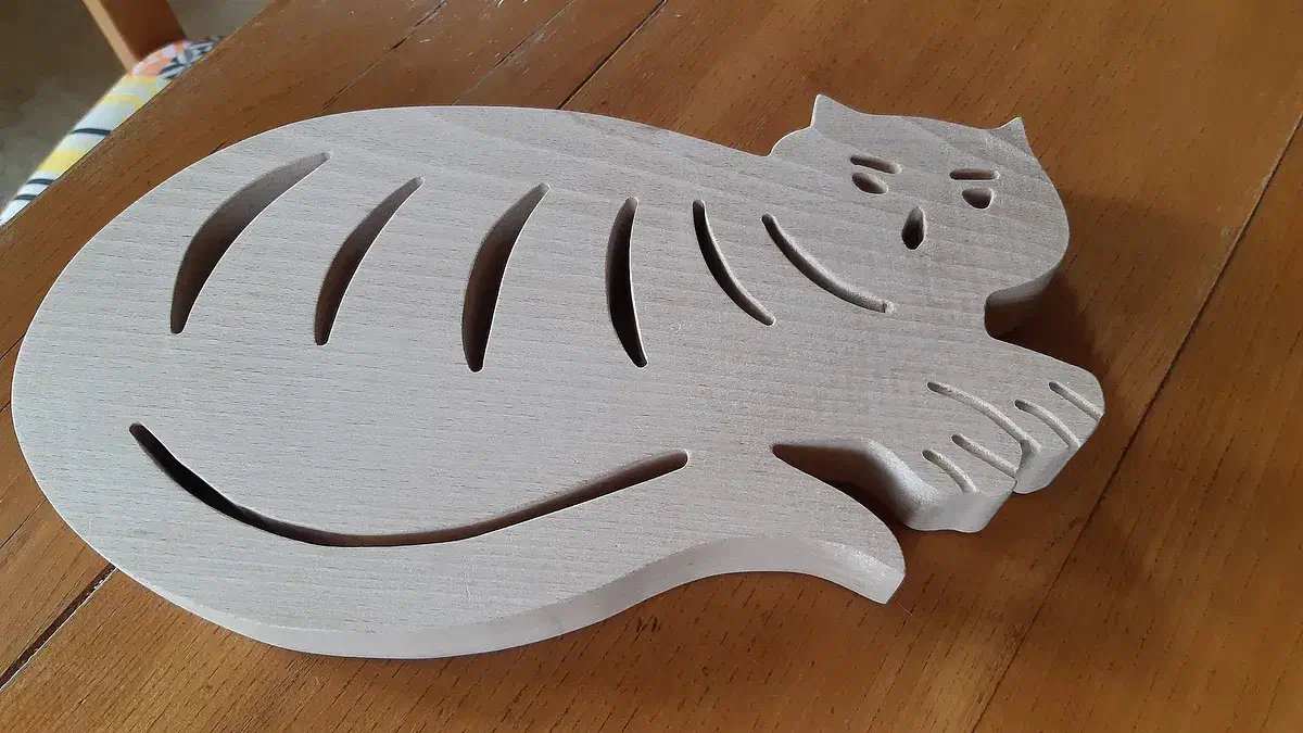 Pale cat-shaped wooden hot pad with carved curved slots