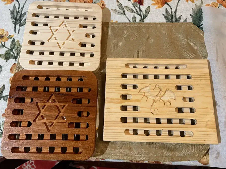 Four slotted wooden trivets with different center motifs